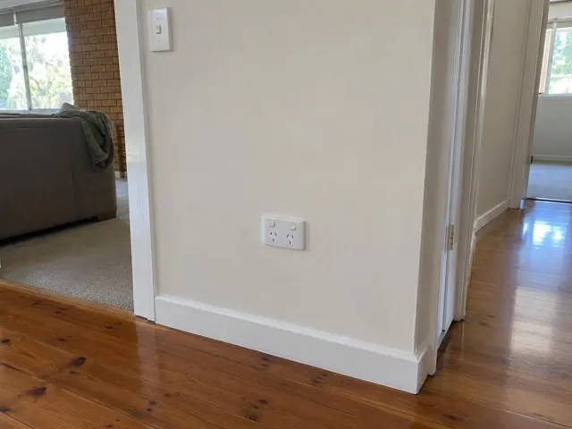 White double power point on painted hallway wall above timber skirting in a home in Upper Coomera